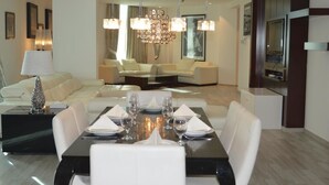 A modern dining area with a black table set for six, white chairs, and a chandelier above.