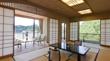 A traditional Japanese room with tatami flooring, a low table, chairs, and sliding doors.