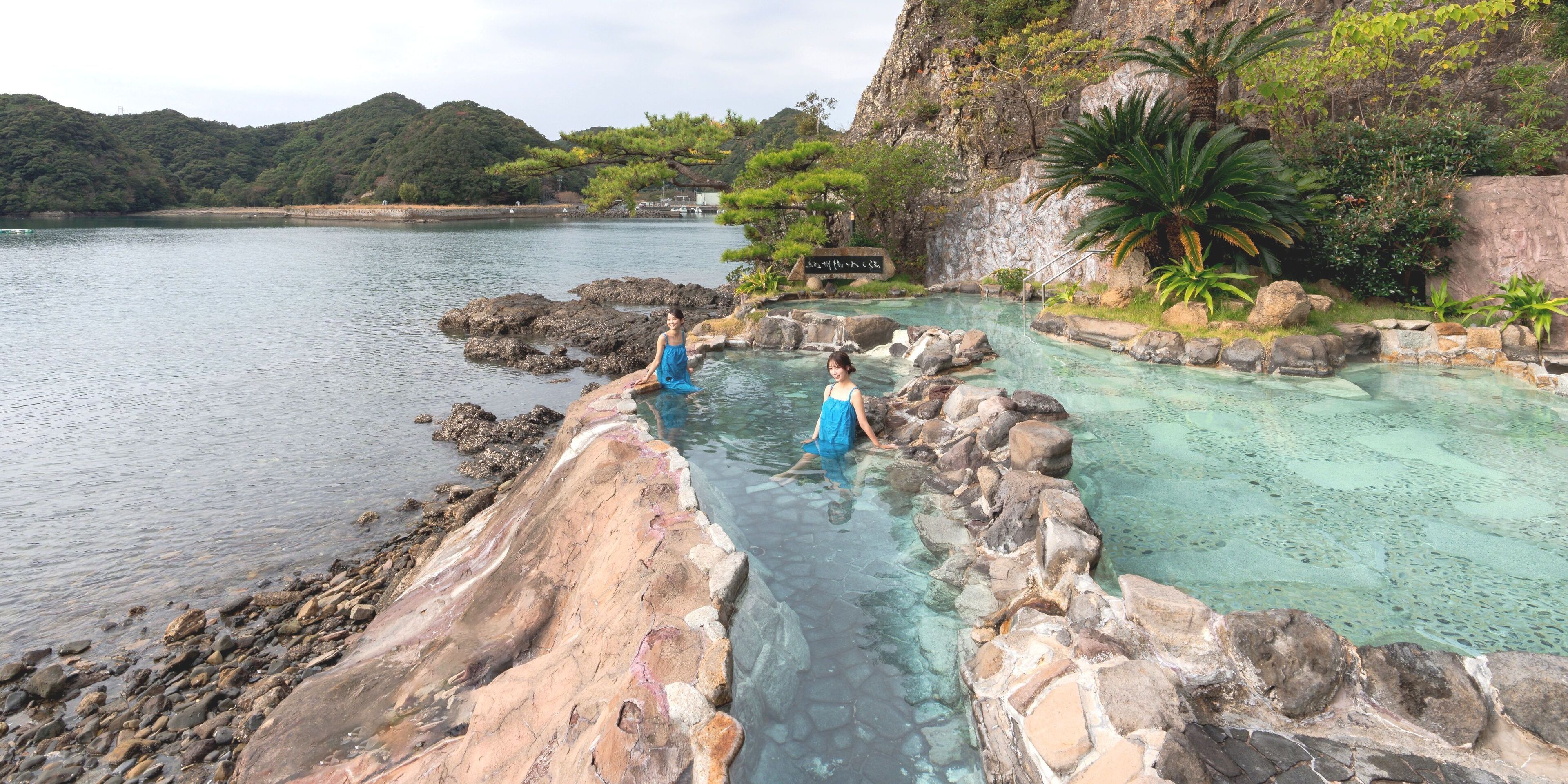 A natural hot spring area with rocky formations and clear water.