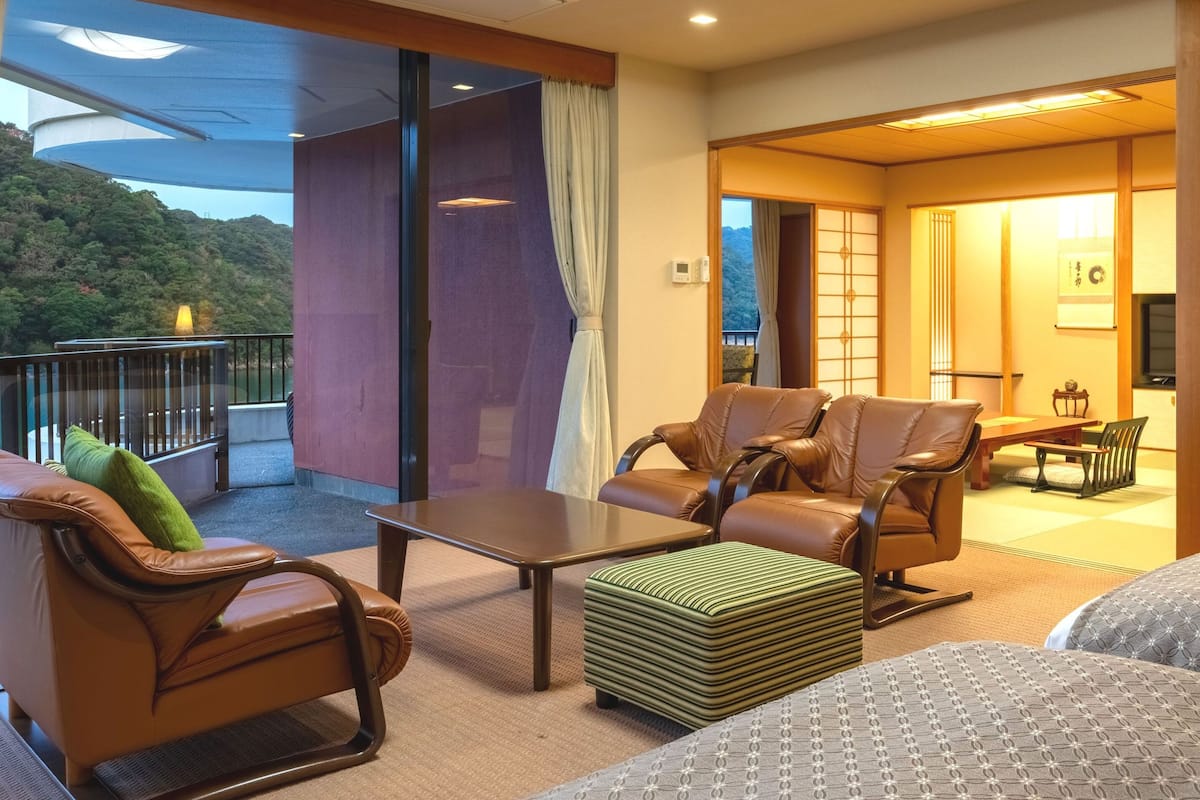 A hotel room with a balcony, a dining area, and a TV.