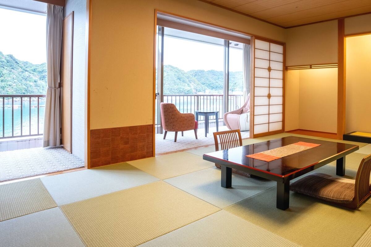 A traditional Japanese room with tatami flooring, a low table, and chairs.