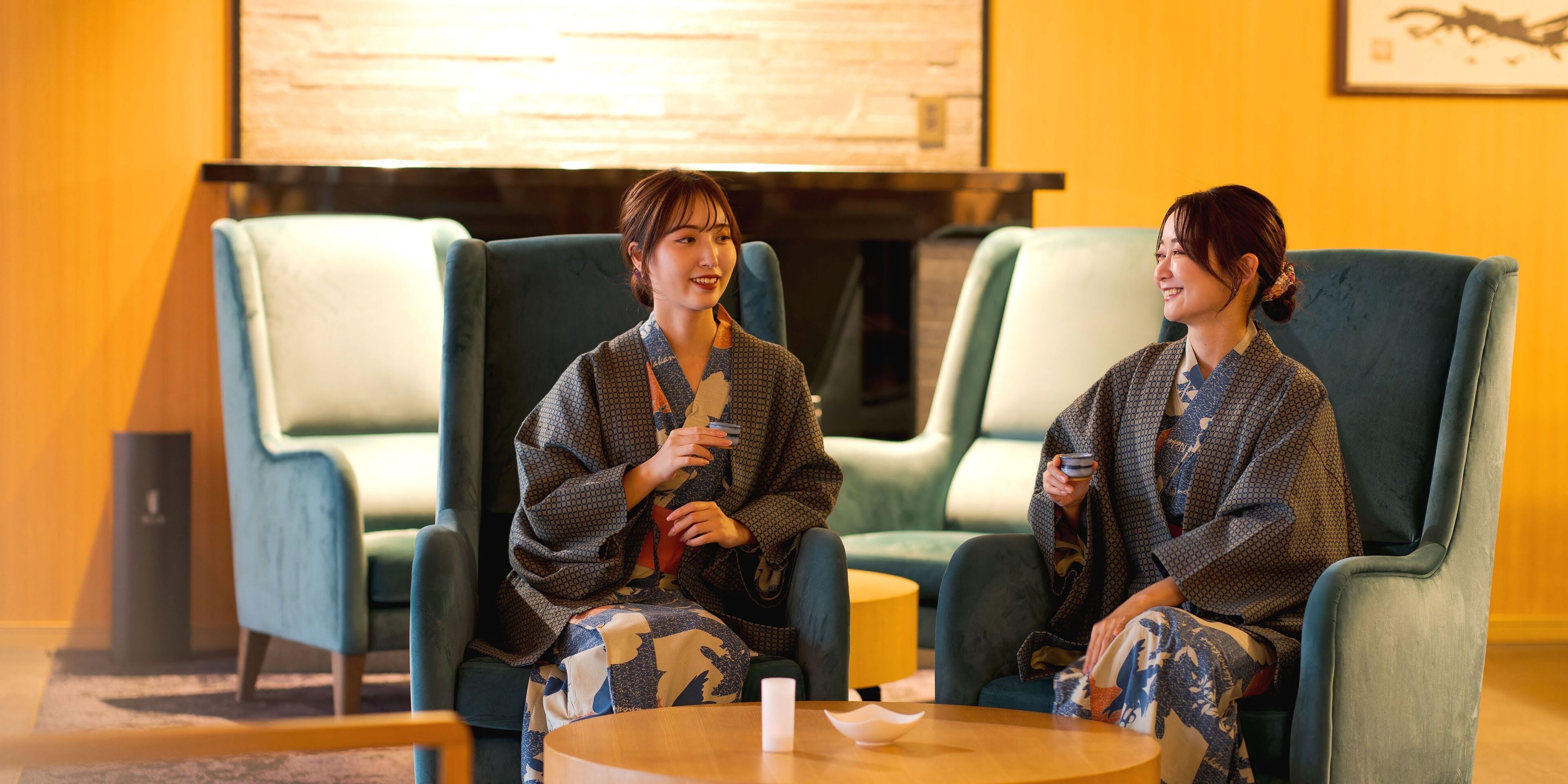 Two people seated in a room with blue chairs and a round table.