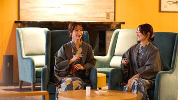 Two people seated in a room with blue chairs and a round table.