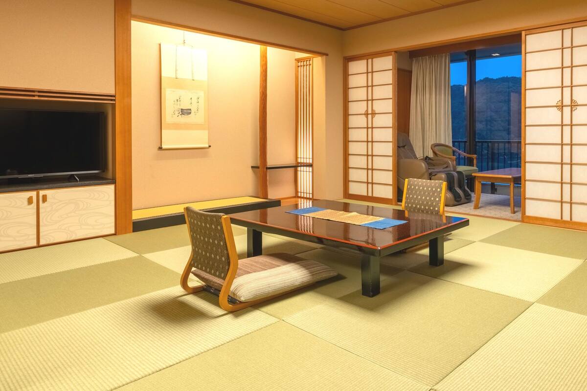 A traditional Japanese room with tatami flooring, a low table, and chairs.