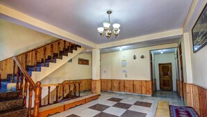 Ein geräumiger Flur mit einer Holztreppe, einem Chandelier und einem gemusterten Teppich.