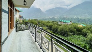 Ein Balkon mit Blick auf eine gebirgige Landschaft, ein Gebäude mit grüner Dachbegrünung und einem klaren Himmel.