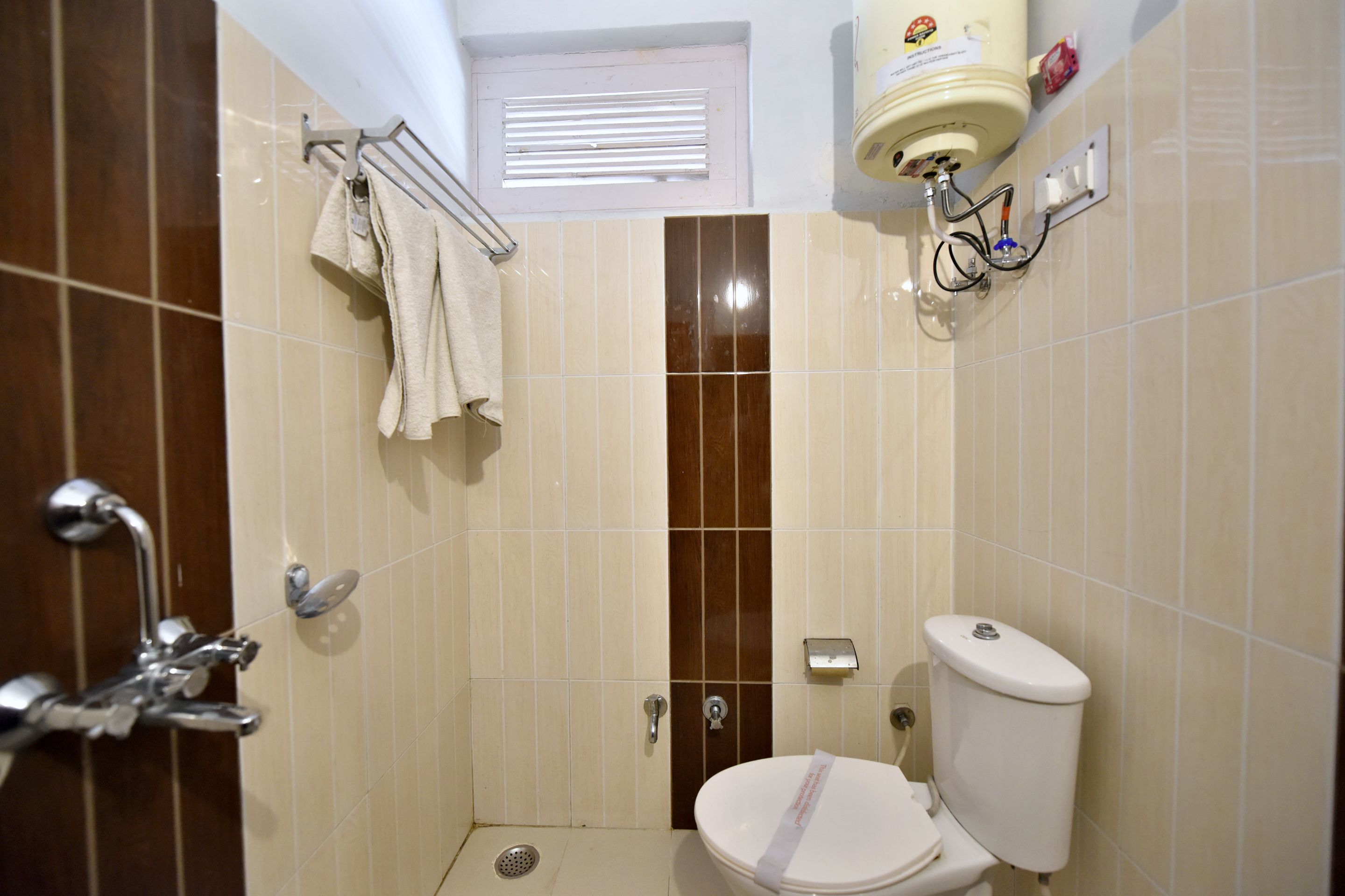 A bathroom with a toilet, shower, and towel rack.