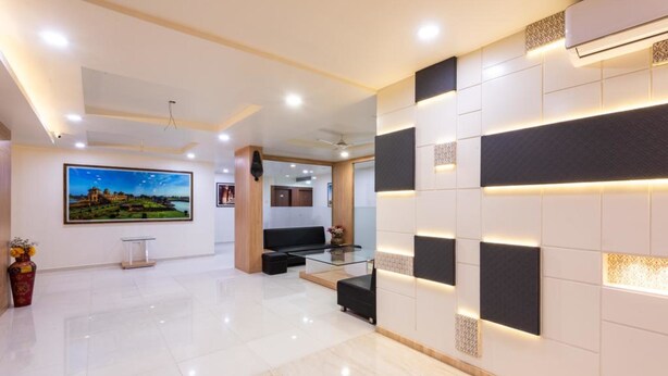 Una moderna hall d'albergo con pavimento lucido, una reception, una zona relax e un'ampia cornice con un quadro appeso al muro.