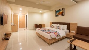 Una camera d'albergo moderna con un letto grande, un divano, una TV e una ventola a soffitto.