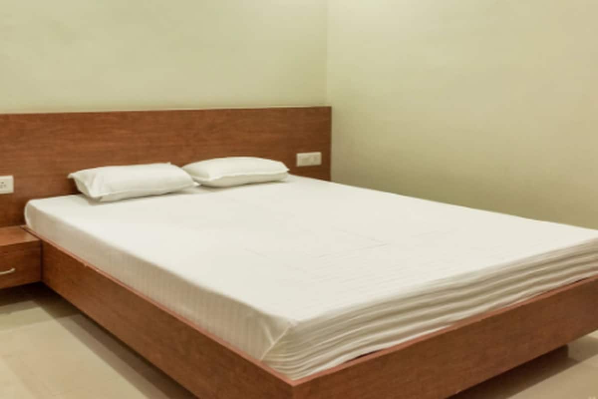 A neatly made bed in a hotel room with a wooden headboard and a small bedside table.