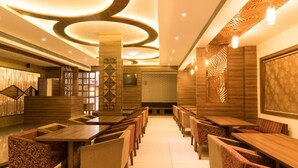 Un ristorante con tavoli e sedie di legno, una parete decorata con un motivo e un moderno design del soffitto.