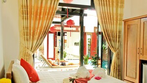 Habitación de hotel con cama, cortinas, un mueble de madera y vistas al exterior.