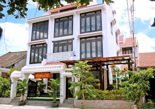 A multi-story building with a balcony, potted plants, and a sign indicating it is a hotel. - Green Island Hoian Villa (Da Nang)