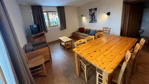 A cozy living room with a wooden dining table, a sofa, and a TV. - Pracondu 1 002 - OUTDOOR & FUN  charming apartment (Haute-Nendaz)