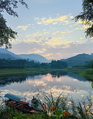 A calm lake with boats and greenery around. - Vu Linh Farmstay - Hostel (Thac Ba)