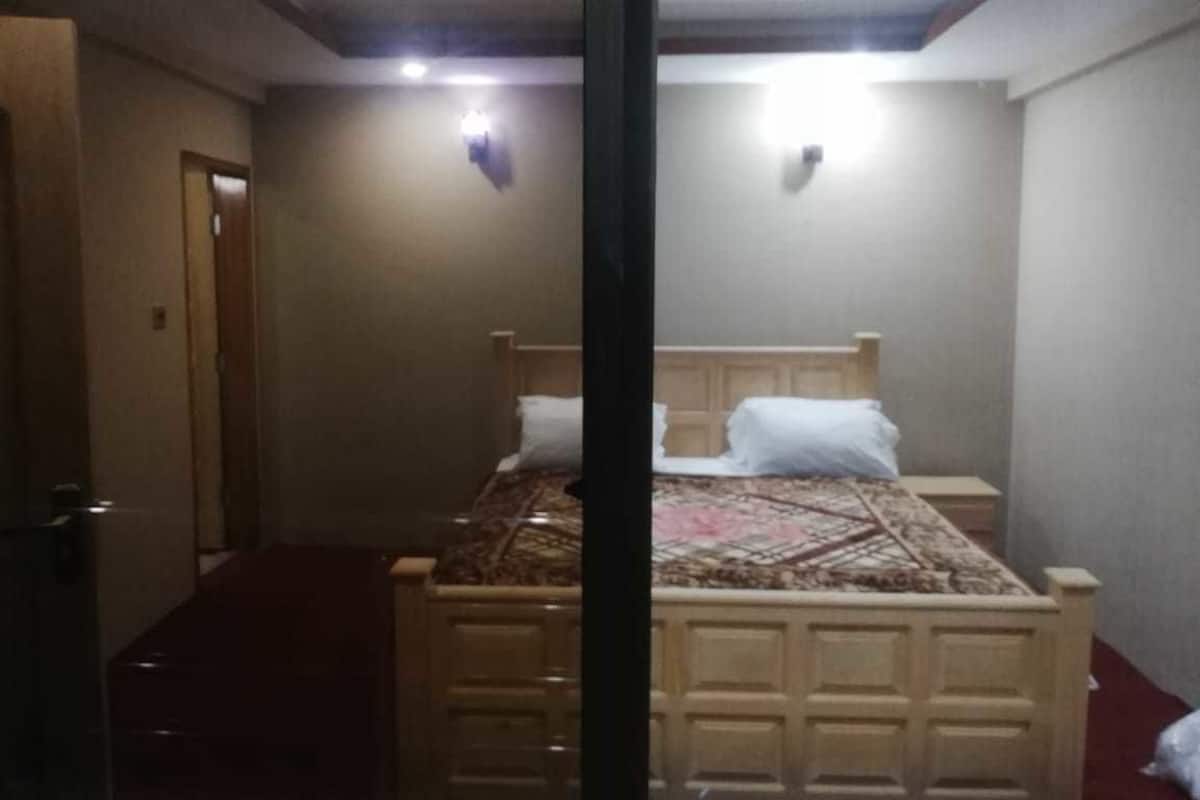 Een slaapkamer met een bed, nachtkastjes en een deur.