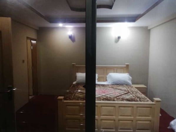 A bedroom with a bed, bedside tables, and a door. - The Lodge Sharda Neelum Valley (Muzaffarabad)