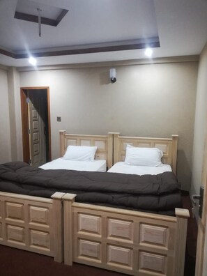 A double bed with a wooden headboard and footboard, a white mattress, and a dark blanket. - The Lodge Sharda Neelum Valley (Muzaffarabad)