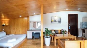 Una habitación acogedora con techo de madera, una cama, un escritorio pequeño, una mesa de comedor con sillas y una planta en maceta.