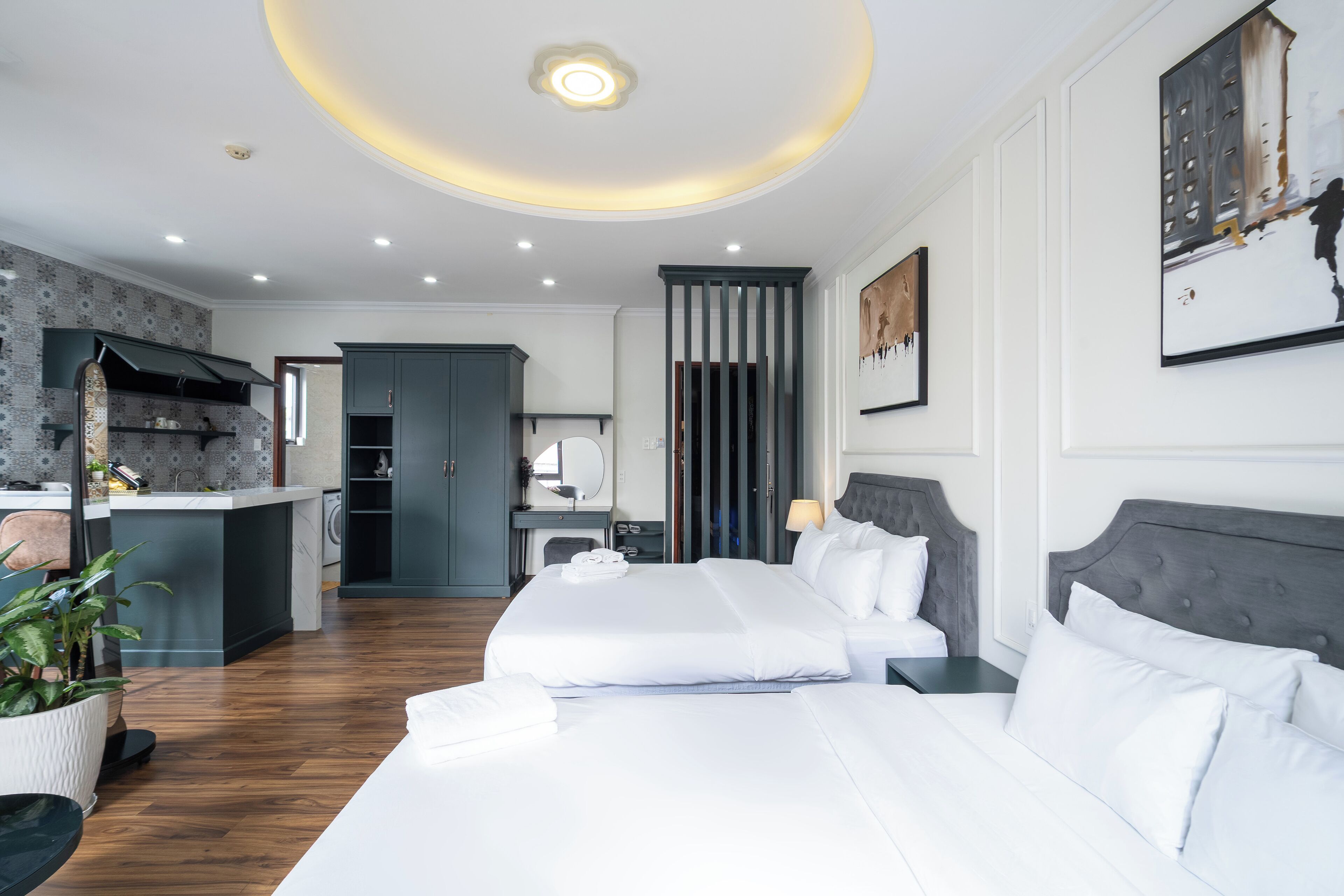 A modern hotel room with a large bed, a separate seating area, and a kitchenette.