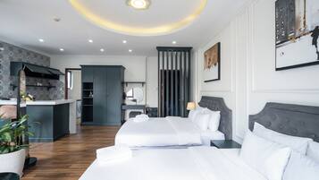 A modern hotel room with a large bed, a separate seating area, and a kitchenette.