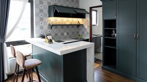 A modern kitchen with a central island, dark cabinetry, and a patterned backsplash. - N Queen Apartment Hotel (Xuan Huong - Da Lat)
