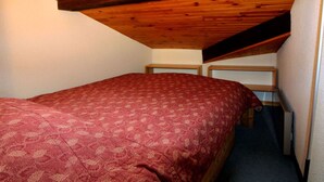 Una habitación pequeña con cama individual, techo inclinado y tragaluz.