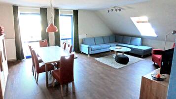 Una sala de estar moderna con comedor, un sofá azul, una mesa de centro redonda y una silla roja.