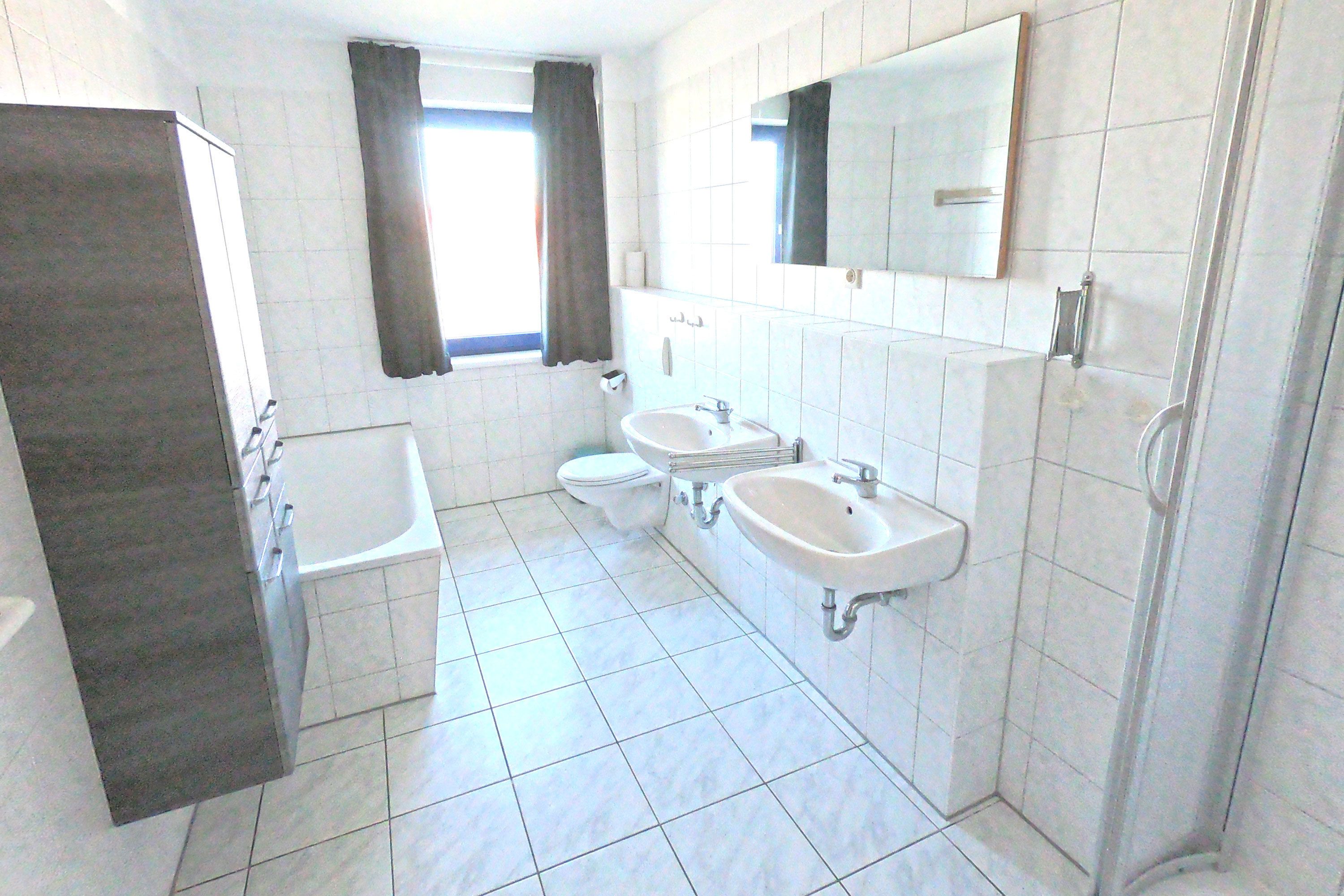 A bathroom with a bathtub, two sinks, a toilet, and a shower.