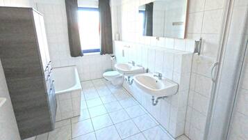 A bathroom with a bathtub, two sinks, a toilet, and a shower.