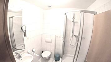 A bathroom with a sink, toilet, and glass-enclosed shower.