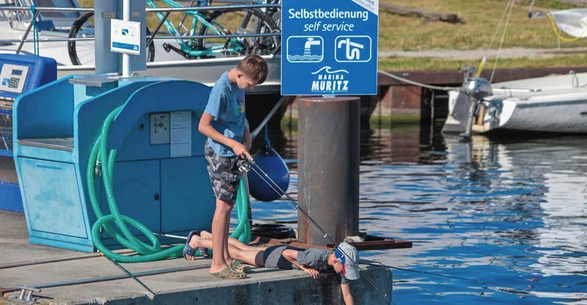 Ein Yachthafen mit Selbstbedienungsstation, einer Anlegestelle und Booten im Hintergrund.