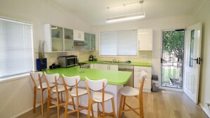 Een moderne keuken met een groen kookeiland, witte kasten en houten stoelen.