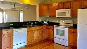A kitchen with wooden cabinets, a microwave, a stove, and a dishwasher. - Shanina Condo.. suit (Carroll)
