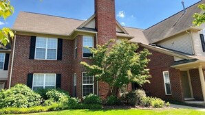 A two-story brick building with a central chimney, a front porch, and a well-maintained lawn. - Shanina Condo.. suit (Carroll)