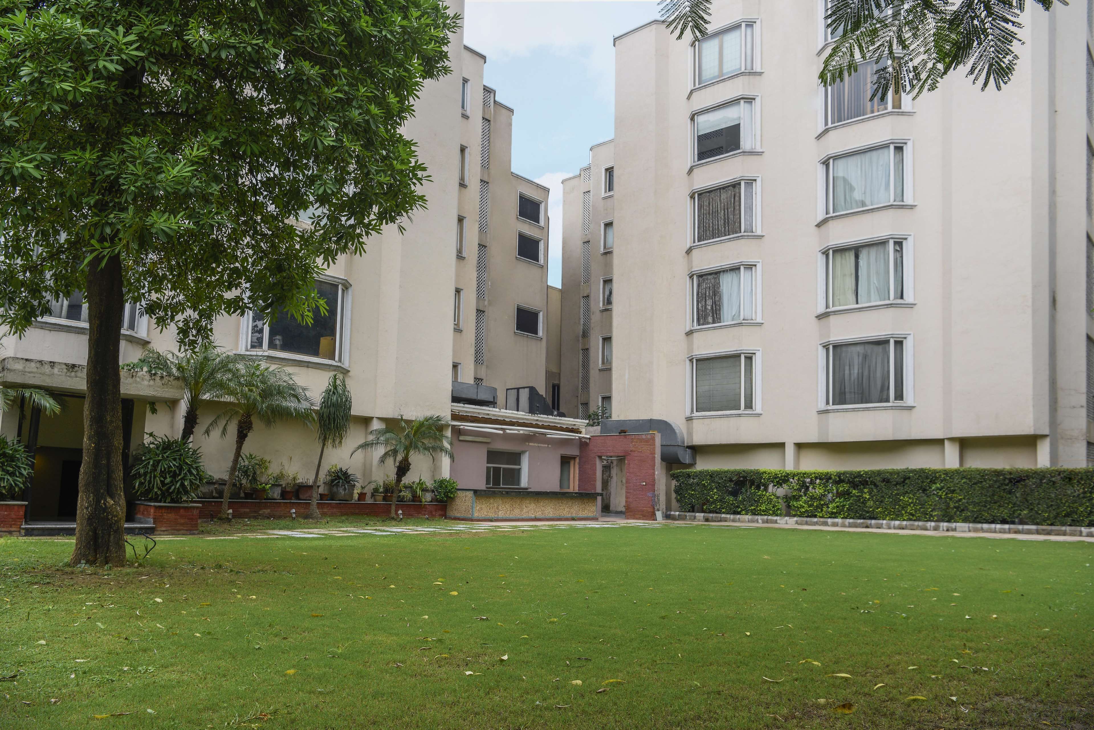 A multi-story residential building with a flat roof, large windows, and a well-maintained lawn.