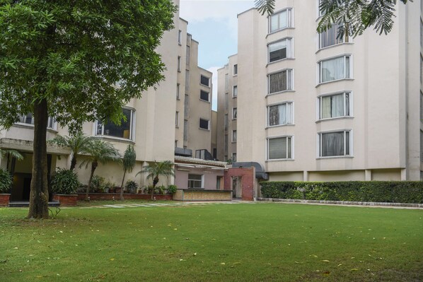 A multi-story residential building with a flat roof, large windows, and a well-maintained lawn. - Sarovar Portico Surajkund Faridabad (Faridabad)