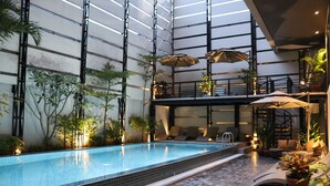An indoor swimming pool with tiled walls and a tiled floor, surrounded by potted plants and lounge chairs. - CHECK inn Phnom Penh BKK 1 (Phnom Penh)
