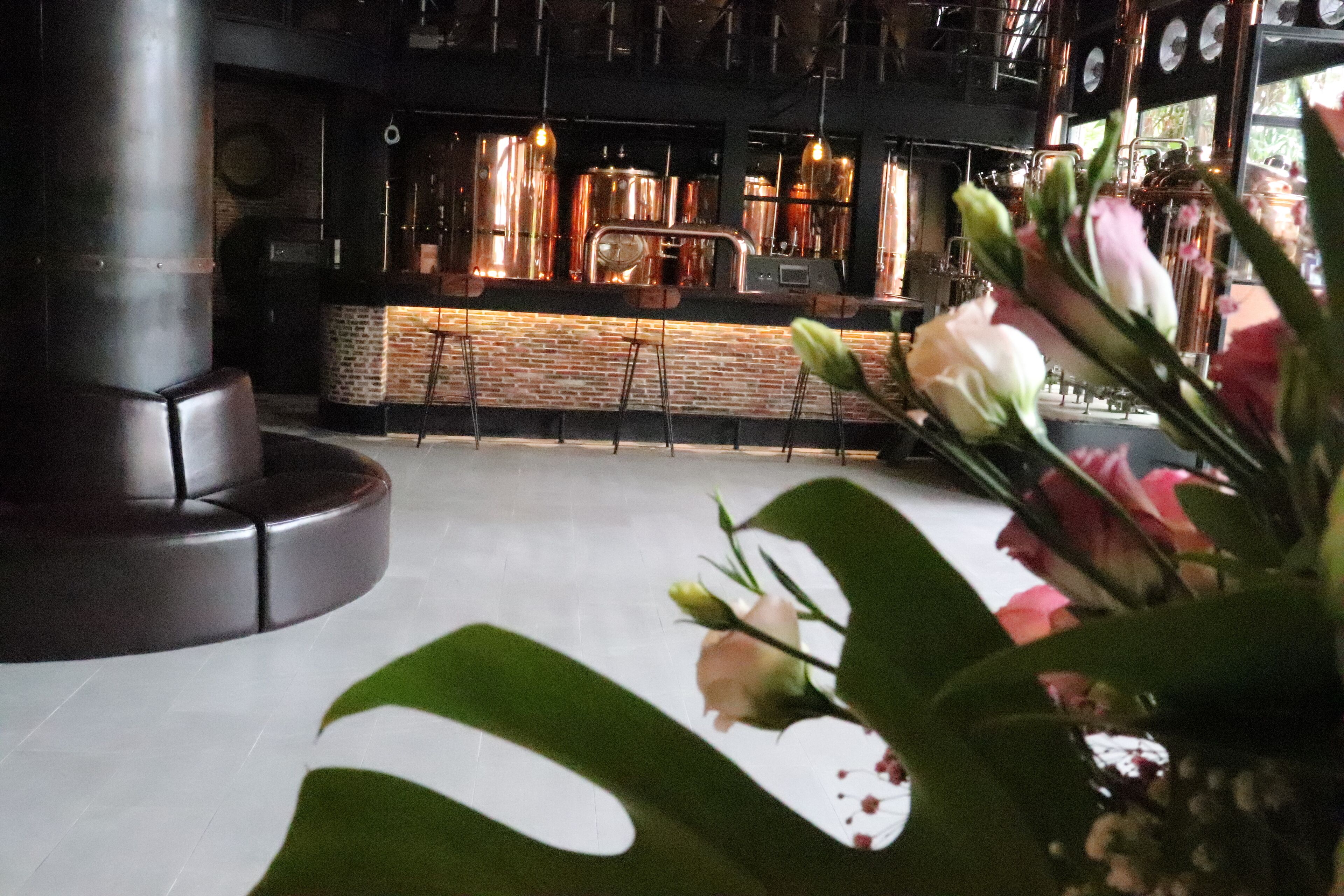 Un espace bar avec un mur en briques, des robinets à bière en cuivre et des luminaires suspendus.