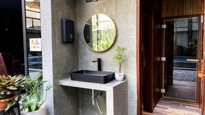 A modern bathroom with a black sink, a round mirror, and a potted plant. - CHECK inn Phnom Penh BKK 1 (Phnom Penh)