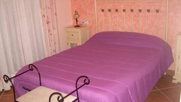 A bedroom with a bed, a nightstand, a lamp, and a chair.