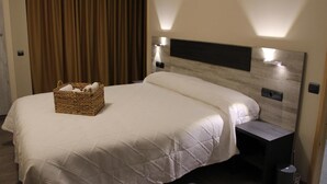 A hotel room with a large bed, a headboard with integrated lighting, a bedside table, and a wicker basket on the bed. - Ca L'angels (Prat de Comte)