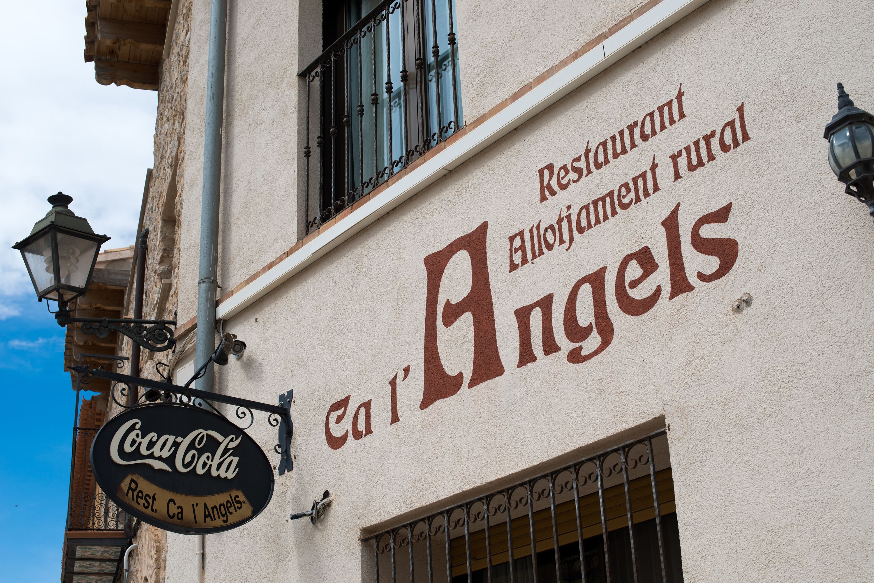 Ein Gebäude mit einem Schild für 'Rest. Ca l'Angels' und einem Coca-Cola-Schild.
