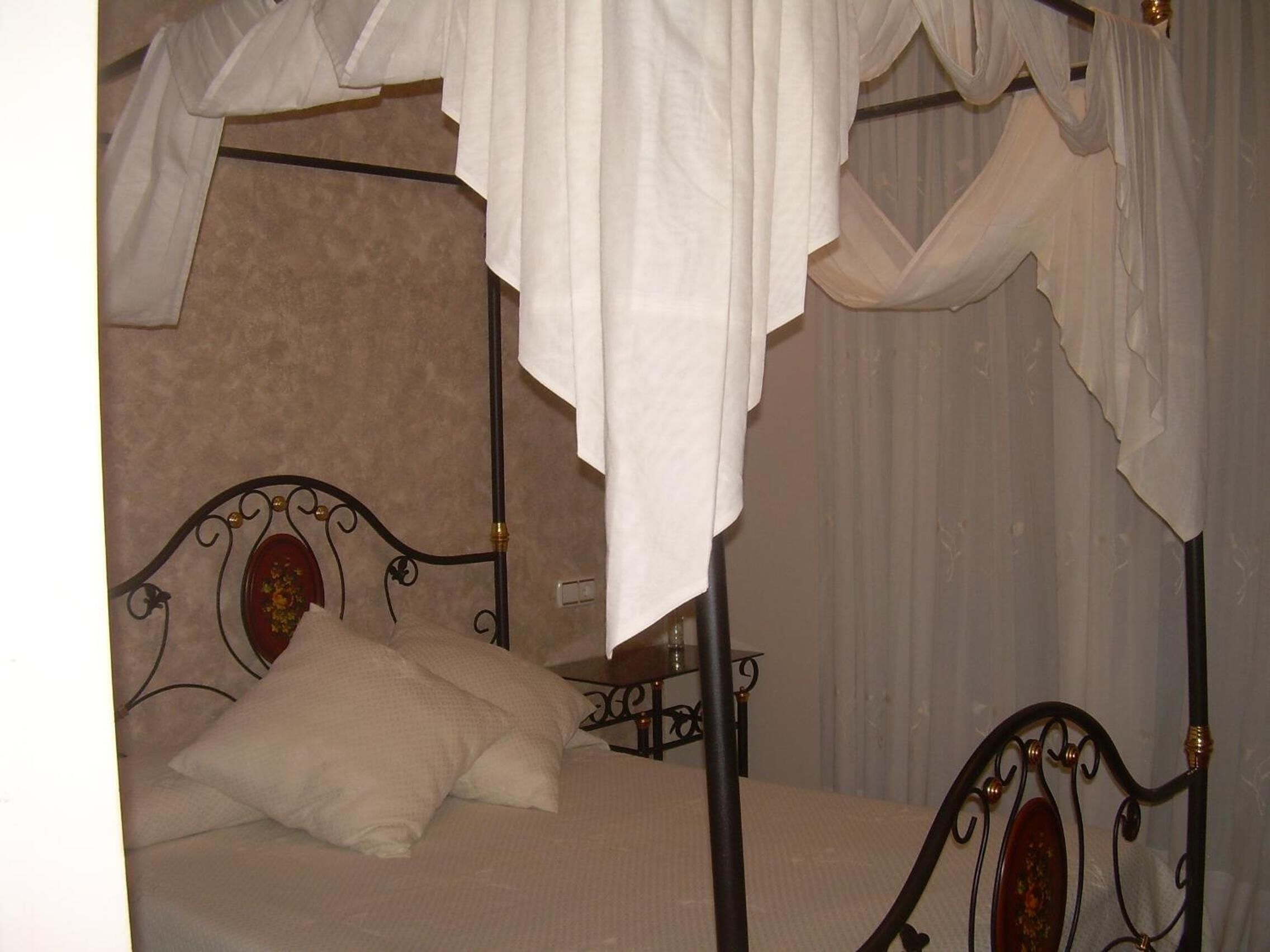 Una cama con dosel, una mesita de noche y una pared con un panel decorativo.