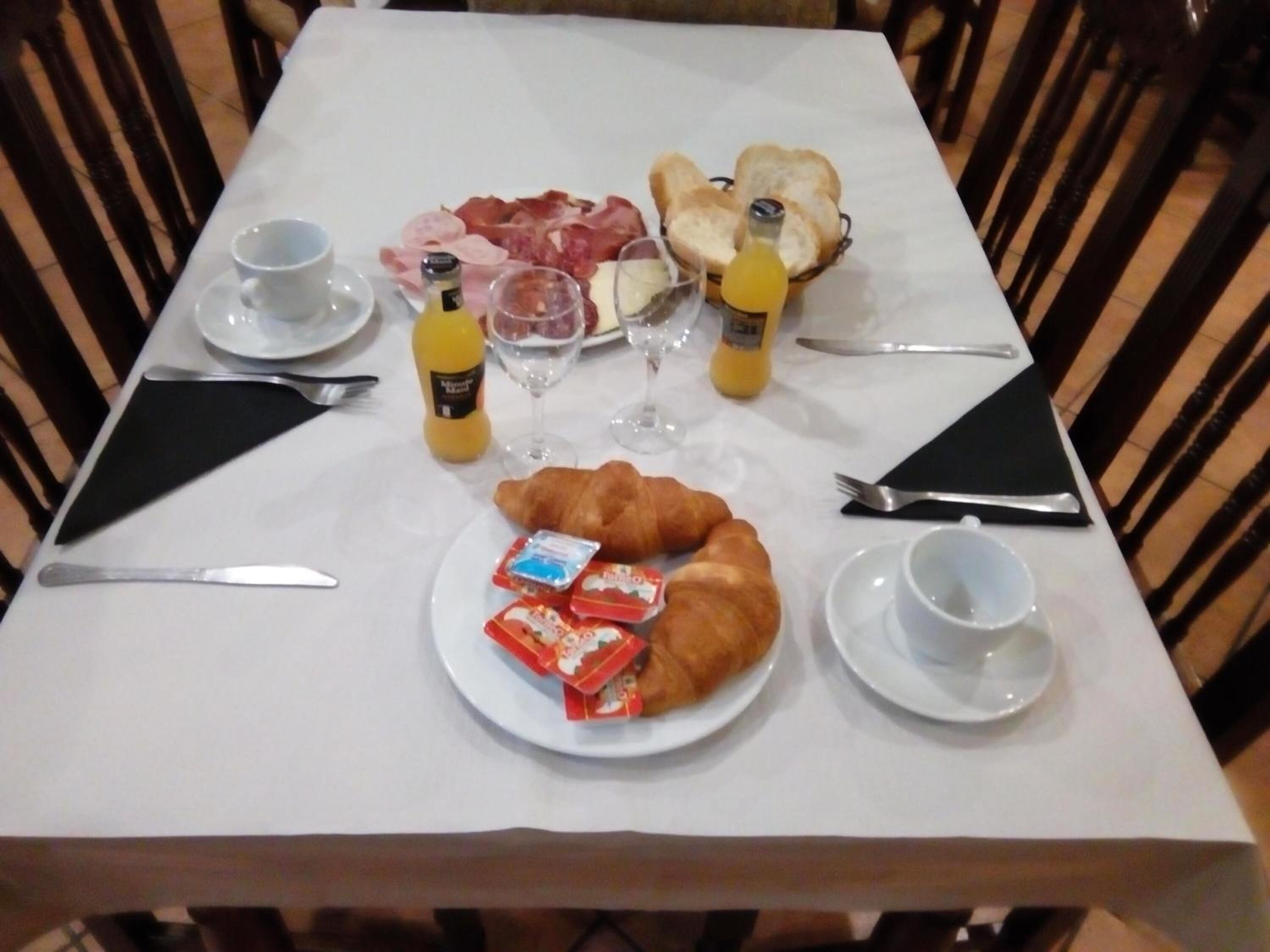 Ett frukostbord med croissanter, ost, skinka, bröd och olika tillbehör.