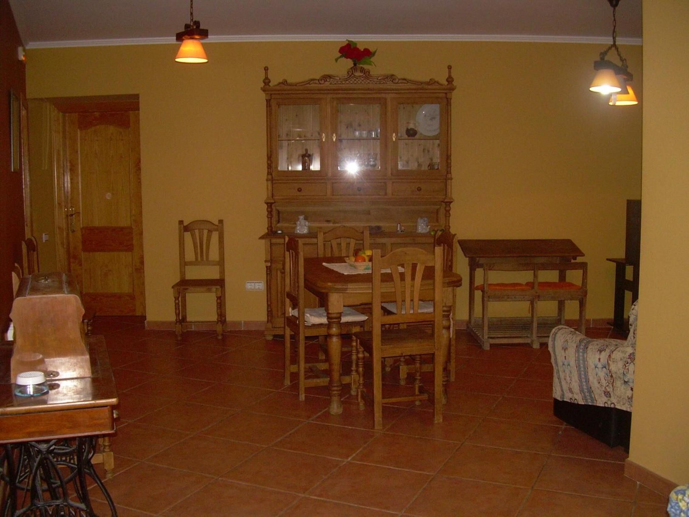 Un coin repas comprenant un buffet en bois, des chaises, une table et des luminaires suspendus.