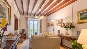 A cozy living room with a sofa, wooden beams, a dining table, and a TV. - Aire Can Pieres, Finca 5StarsHome Mallorca (Esporlas)