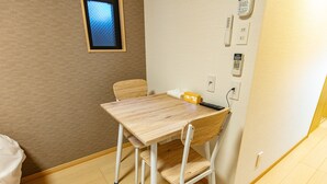 A small room with a wooden table and a chair, a bed, and a wall-mounted phone. - F Plus Inn Tofukuji (Kyoto)