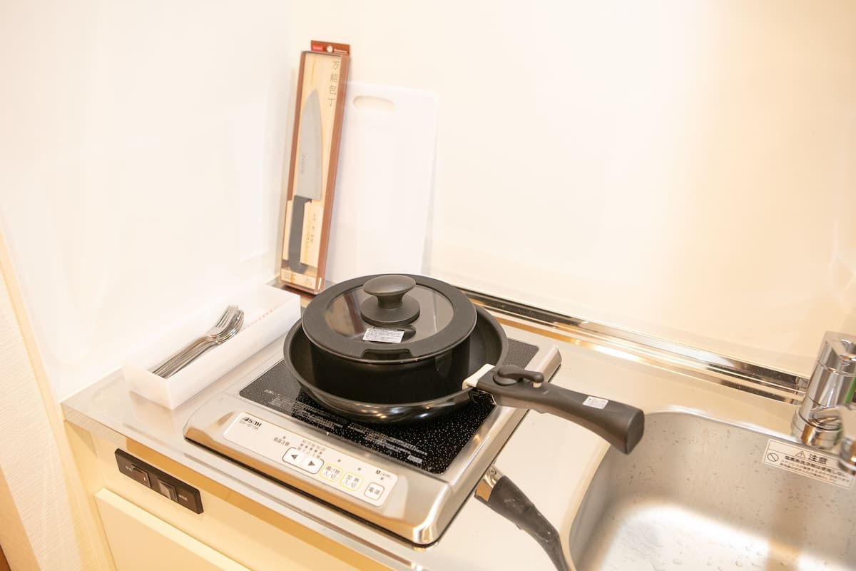 A kitchen with a stove, a pot, a cutting board, and a sink.