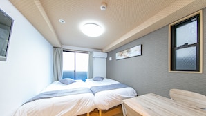 A bedroom with two beds, a window, a desk, and a ceiling light. - F Plus Inn Tofukuji (Kyoto)